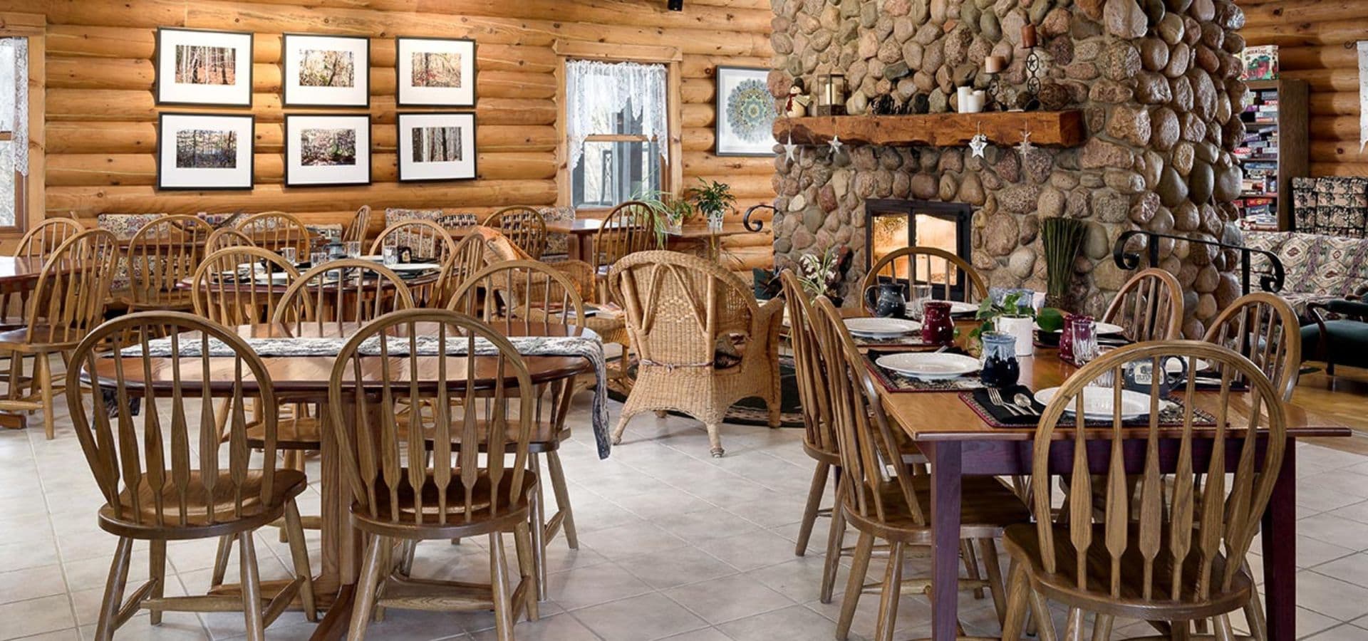 Cozy restaurant interior with wooden furniture and a stone fireplace.